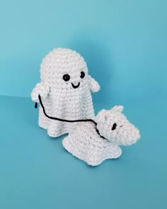 two white crocheted stuffed animals sitting next to each other on a blue background