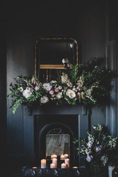 a fireplace with candles and flowers on it