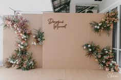 an outdoor event with flowers and greenery on the wall