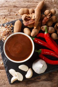 hot chocolate sauce in a white bowl surrounded by nuts, garlic and peppers on a slate board