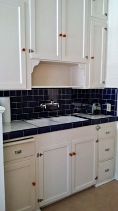 a kitchen with white cabinets and dark blue counter tops is pictured in this image, it appears to be empty