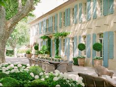 an outdoor dining area with wicker chairs and tables in front of a large house