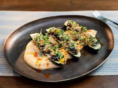 a black plate topped with food on top of a wooden table