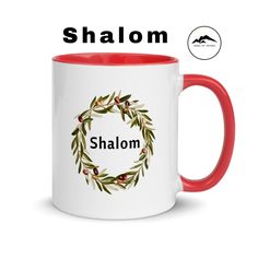 a red and white coffee mug with the word shaloh on it, surrounded by an olive wreath