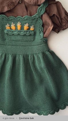 a green knitted dress with three little birds on the front and two brown ruffled sleeves