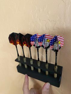 a person is holding a set of five patriotic wind chimes on a black stand