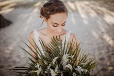 a woman holding a bouquet of flowers in her hands and looking down at the ground