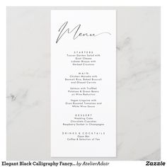 the menu card for a wedding is shown on a marble tablecloth with white and black ink