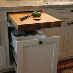 a cutting board on top of a cabinet in a kitchen with white cabinets and drawers