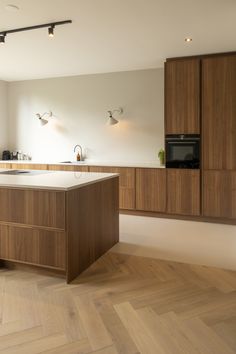 an empty kitchen with wooden cabinets and white counter tops, along with hardwood flooring