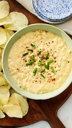 a bowl of dip surrounded by chips on a cutting board