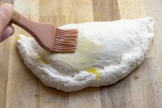 a person using a brush to spread butter on top of dough