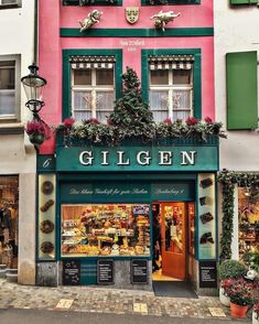 a store front with green shutters and flowers on the window sill above it