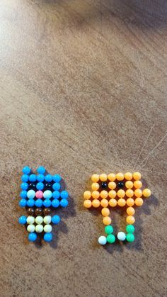 two pieces of bead art sitting on top of a wooden table next to each other