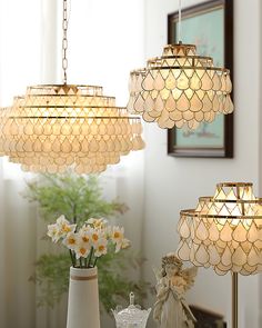 three chandeliers hanging over a table with flowers in vases on it and a potted plant next to them