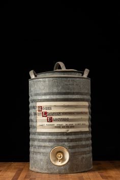 an old metal bucket sitting on top of a hard wood floor in front of a black background