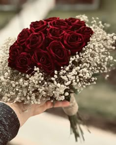 someone holding a bouquet of red roses and baby's breath