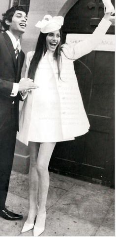 a man and woman standing next to each other in front of a sign with writing on it