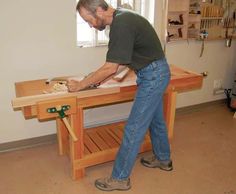 a man sanding on top of a wooden table