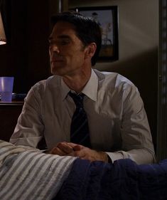 a man sitting in bed wearing a tie