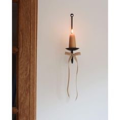 a candle that is on the wall next to a light fixture with a cord wrapped around it