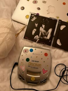 two cd's are sitting on a bed next to an ipod and a ball of yarn