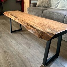 a wooden table sitting on top of a hard wood floor next to a gray couch