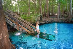 a woman standing in the middle of a blue pool with stairs leading up to it