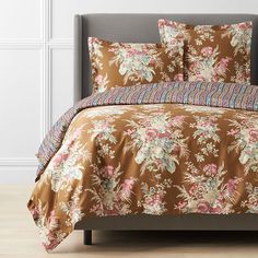 a bed with a brown floral comforter and matching pillow cases on top of it