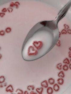 a spoon with the word love on it is in a bowl filled with milk and hearts