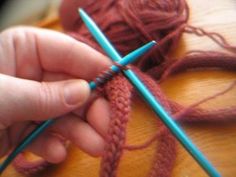 a person is knitting yarn on a table with blue crochet needles in front of them