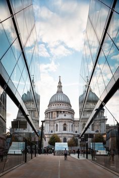 people are walking on the sidewalk in front of some buildings with glass walls and dome tops