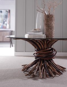 a table that has some books and a vase on top of it with branches in the middle