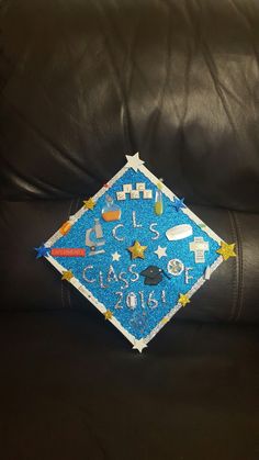 a blue graduation cap sitting on top of a black leather couch next to a pillow