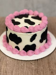 a pink and black cake sitting on top of a white plate next to a wooden table