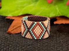 a close up of a bracelet on top of a black surface with leaves in the background