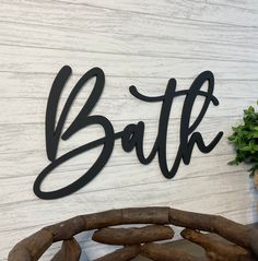 a wooden sign that says bath next to a potted plant