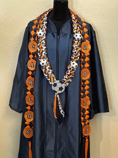 an orange and black graduation gown with beads on the neck, along with a beaded necklace