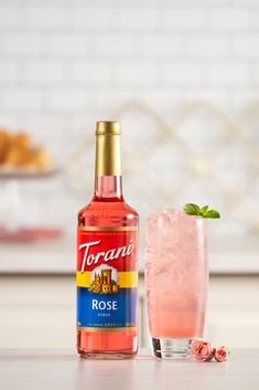 a bottle of rose wine next to a glass filled with ice and garnish