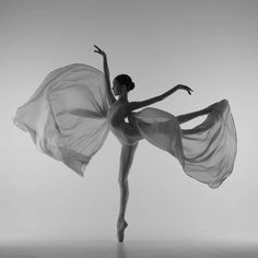 a ballerina in white is posing with her arms spread out and she's wearing a flowing dress