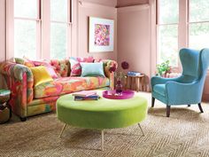 a living room with pink walls and colorful furniture in the center, along with large windows