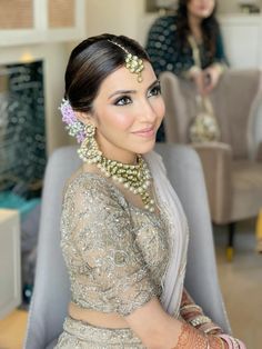 a woman sitting in a chair wearing a bridal outfit with jewelry on her head