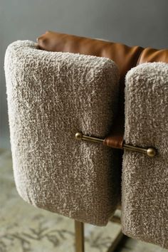 a pair of brown leather and tweed chairs with brass handles, on a carpeted floor