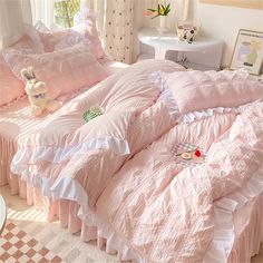 a pink bed with ruffled sheets and pillows