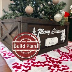 a christmas tree in a wooden crate with the words build plan on it and ornaments