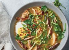 a bowl of soup with meat, vegetables and an egg in it on a table