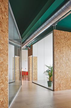 an empty room with glass walls and wood panels on the wall, along with a potted plant