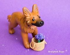 a dog figurine is standing next to a basket with purple flowers in it