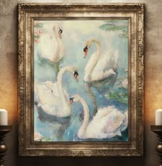 a painting of swans floating on water with candles in front of it and an ornate gold frame