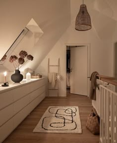 an attic bedroom with white walls and wooden flooring has a rug on the floor